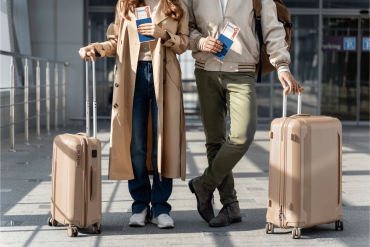 Deux voyageurs avec des valises tenant des billets d’avion, marchant dans un terminal d’aéroport.