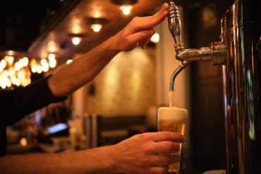 Personne servant une bière pression au comptoir d’un établissement horeca.
