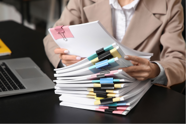 Personne consultant et classant une pile de documents sur un bureau.