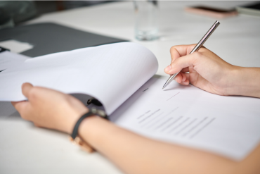 Personne signant ou complétant un document posé sur un bureau.